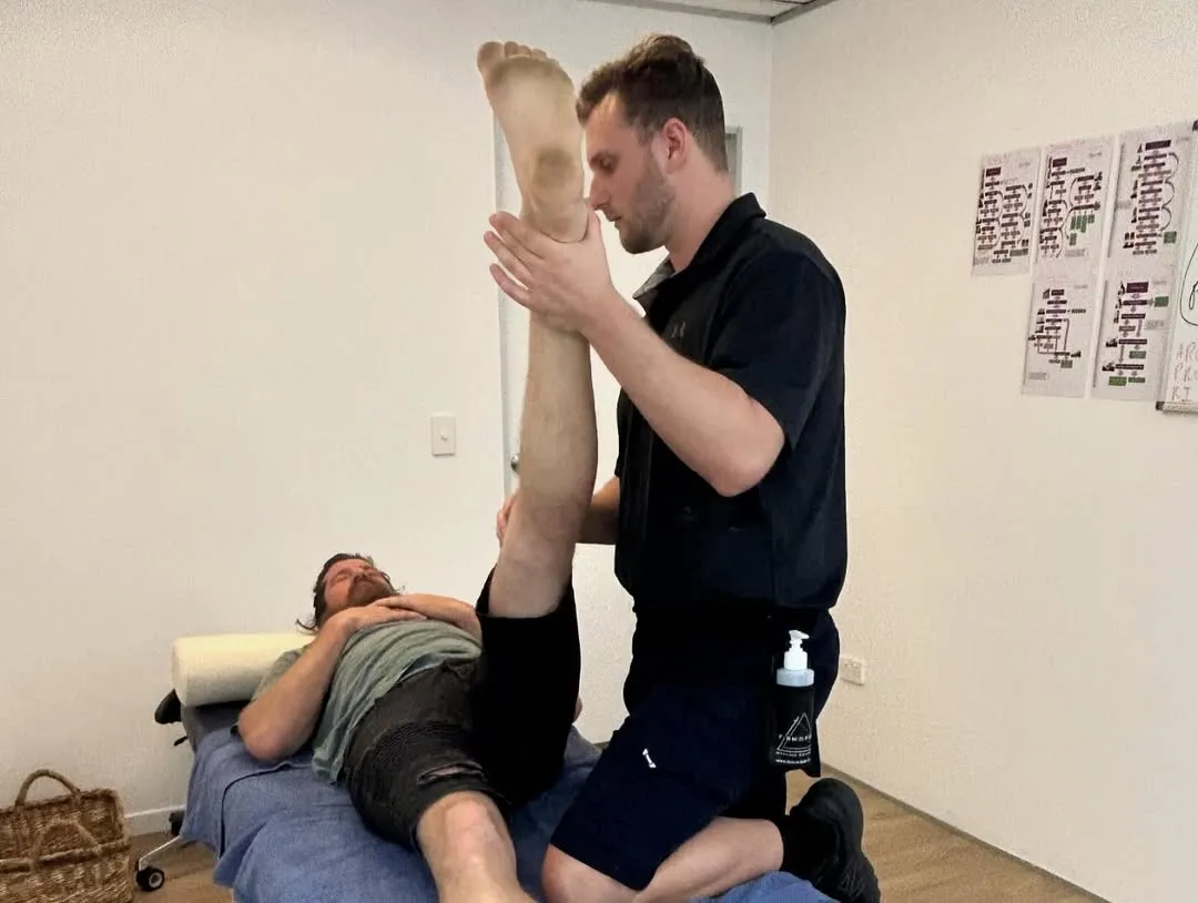 Physical therapist stretching patient's leg on table