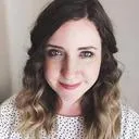 Smiling person with wavy hair and white shirt.